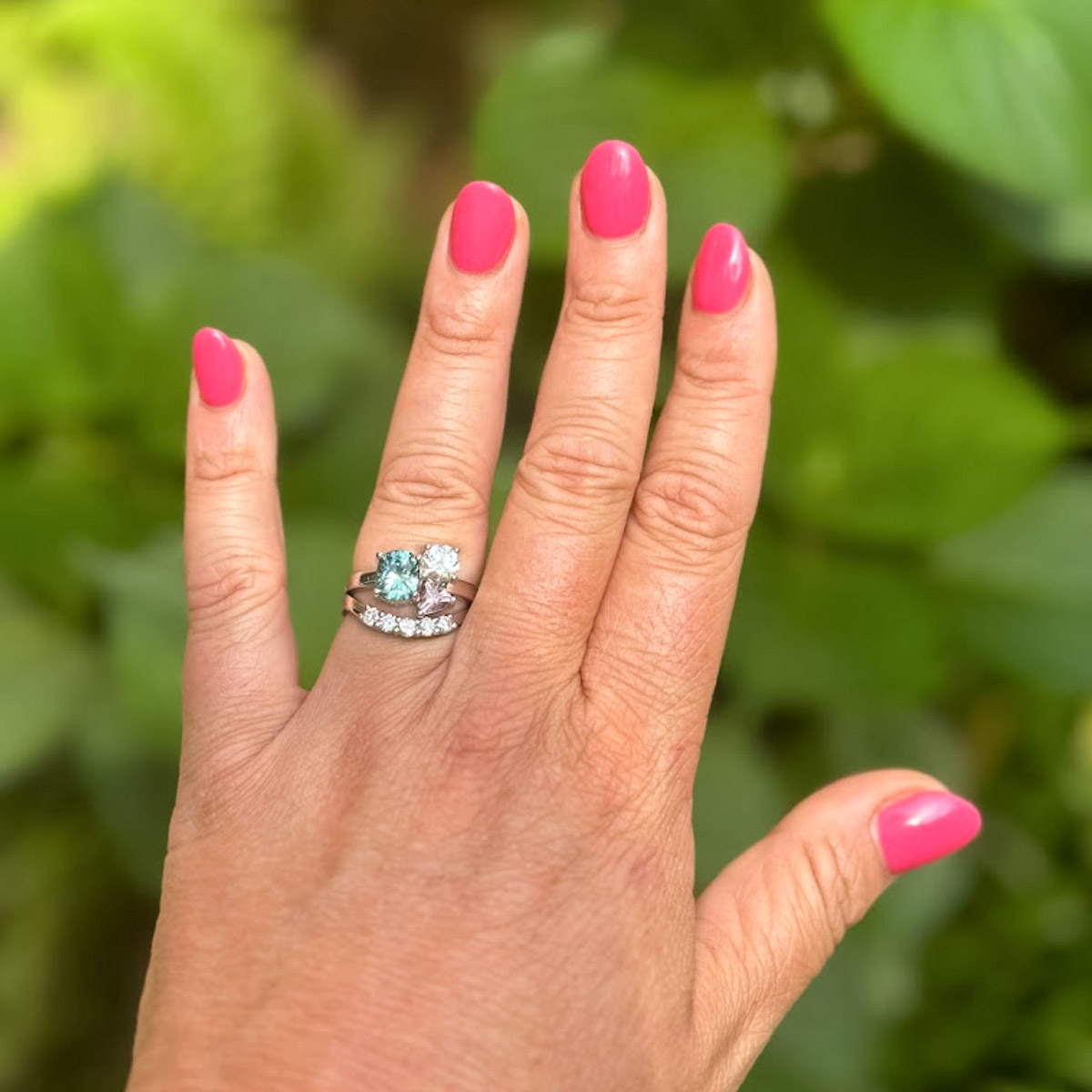 A custom ring set in 14K white gold, featuring heirloom diamonds, a 2.08-carat teal sapphire, and a 0.65-carat pink sapphire