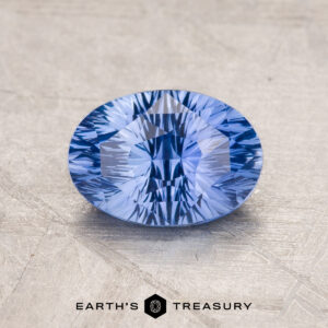 A faceted blue 1.82-carat Ceylon Sapphire is displayed on a gray surface, with the text "Earth's Treasury" and its logo visible at the bottom.