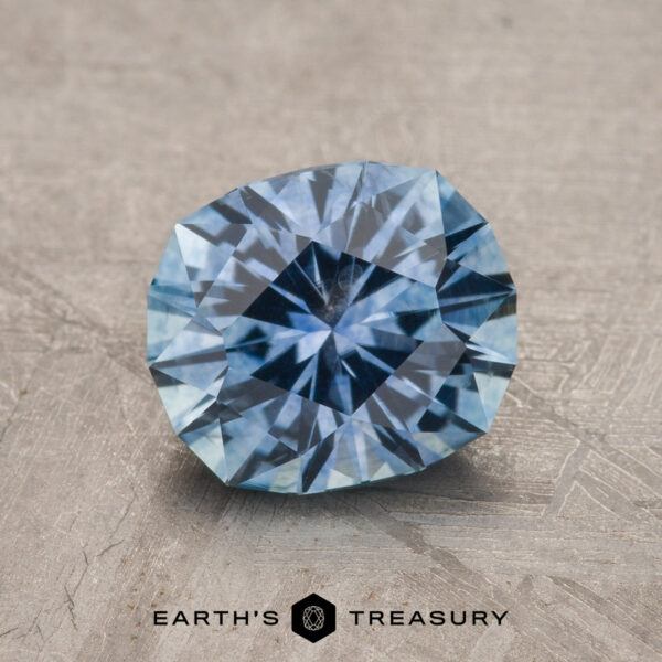 1.89-Carat Sky Blue Montana Sapphire (Heated) A 1.89-carat Sky Blue Montana Sapphire (Heated) with a starburst pattern rests on a textured gray surface above the text "Earth's Treasury.