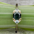 The "Lillium" ring in 14k yellow gold, featuring a 1.38-carat Australian sapphire and two light blue stones, is shown on a green leaf background with the "Earth's Treasury" logo below.
