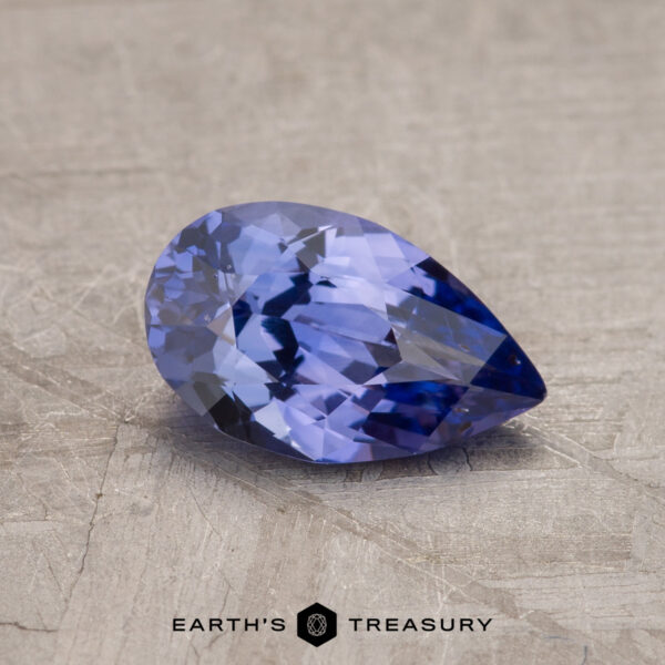 1.15-Carat Violet Purple Ceylon Sapphire A pear-shaped, faceted blue gemstone rests on a textured surface. The text "EARTH'S TREASURY" is visible at the bottom of the image. This is the 1.15-Carat Ceylon Sapphire.