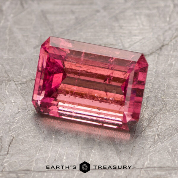 2.70-Carat Intense Pink California Tourmaline A rectangular pink gemstone, identified as ET1382, is displayed on a textured surface with the words "EARTH'S TREASURY" below it.