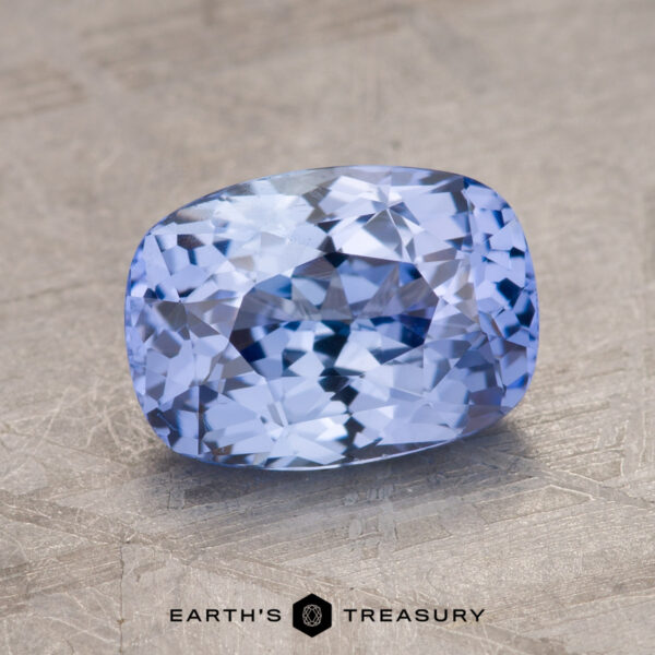 2.09-Carat Light Violet-Blue Ceylon Sapphire The 2.09-Carat Celyon Sapphire, a faceted, rectangular light blue gemstone with intricate internal reflections, is placed on a textured gray background.
