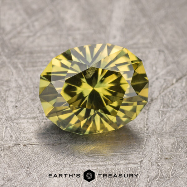 2.23-Carat Greenish Yellow Australian Sapphire (Heated) A 2.23-carat Australian yellow sapphire, featuring finely cut facets, rests on a textured surface with the logo "Earth's Treasury" displayed at the bottom.