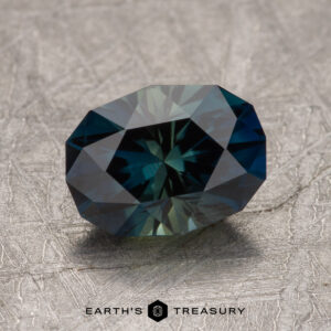 A 2.42-carat Australian sapphire is displayed on a textured surface, with the "Earth's Treasury" logo visible at the bottom center of the image.