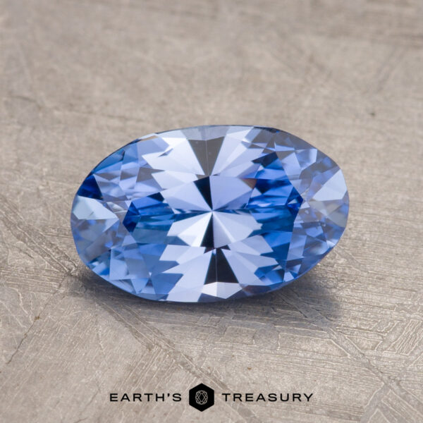 1.57-Carat Ceylon Sapphire A 1.57-carat Ceylon Sapphire, expertly faceted into an oval shape, is displayed against a textured gray background with the "EARTH'S TREASURY" logo prominently positioned at the bottom center.