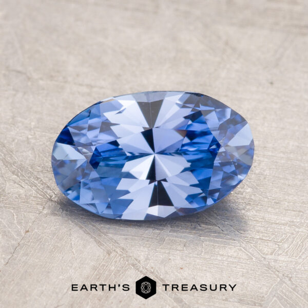1.57-Carat Ceylon Sapphire A 1.57-carat Ceylon Sapphire, expertly faceted into an oval shape, is displayed against a textured gray background with the "EARTH'S TREASURY" logo prominently positioned at the bottom center.