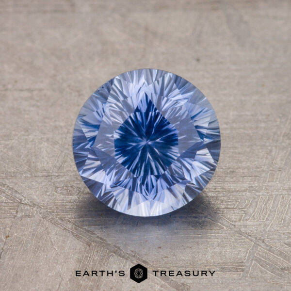 1.99-Carat Ceylon Sapphire A close-up image of a round brilliant-cut blue gemstone on a textured surface with the text "1.99-Carat Ceylon Sapphire" at the bottom.