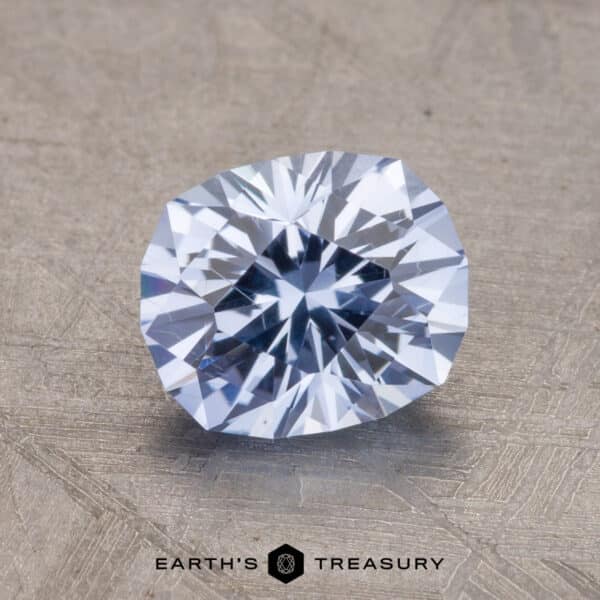 2.48-Carat Ceylon Sapphire A close-up of a faceted pale violet-blue 2.48-Carat Ceylon Sapphire gemstone on a textured surface with the text "Earth's Treasury" at the bottom.