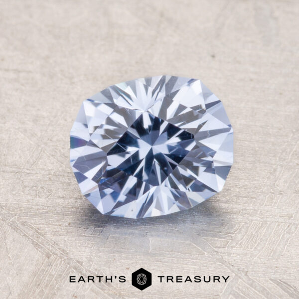 2.48-Carat Ceylon Sapphire A close-up of a faceted pale violet-blue 2.48-Carat Ceylon Sapphire gemstone on a textured surface with the text "Earth's Treasury" at the bottom.