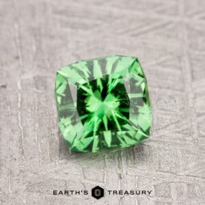 0.97-Carat Tsavorite Garnet in a square shape with faceted cuts on a textured gray surface.