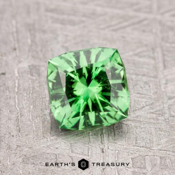 0.97-Carat Tsavorite Garnet in a square shape with faceted cuts on a textured gray surface.