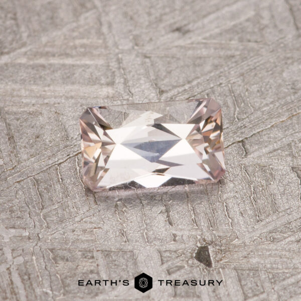 0.50-Carat Unheated Tanzanite (Zoisite) A 0.50-carat Fancy Tanzanite faceted gemstone is placed on a textured surface with the text "EARTH'S TREASURY" at the bottom.