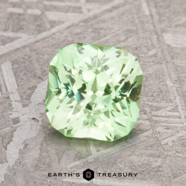 1.67-Carat Mint Green Grossular Garnet A 1.67-carat mint green grossular garnet with a square cut rests on a textured surface. Text below reads "Earth's Treasury.