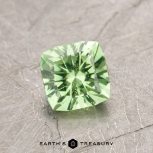 Introducing ET1108: A stunning square-cut green gemstone with precise facets, elegantly displayed on a textured gray surface.