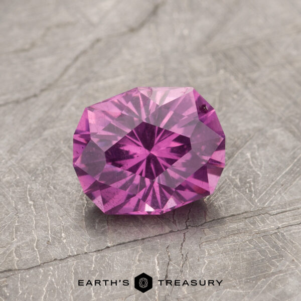 1.29-Carat Pastel Pyrope Color-Change Garnet A faceted gemstone from product ET1127, featuring a pink hue, displayed on a textured gray surface.