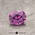 A faceted pink gemstone, product ET1128, rests on a textured gray surface labeled "Earth's Treasury.