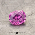 A pink, faceted gemstone sits on a textured surface with "ET1128" written at the bottom.