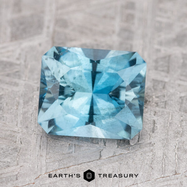 1.78-Carat Nasarawa Teal Aqua A 1.78-carat Nasarawa teal aqua gemstone, rectangular in shape with facets, displayed on a textured gray surface.