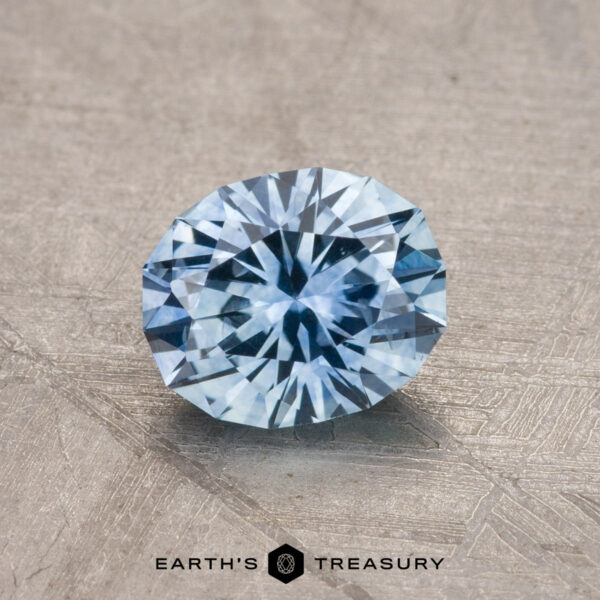 1.19-Carat Montana Sapphire (Heated) A faceted blue gemstone displayed on a textured surface, with the product name "1.19-Carat Montana Sapphire (Heated)" at the bottom.