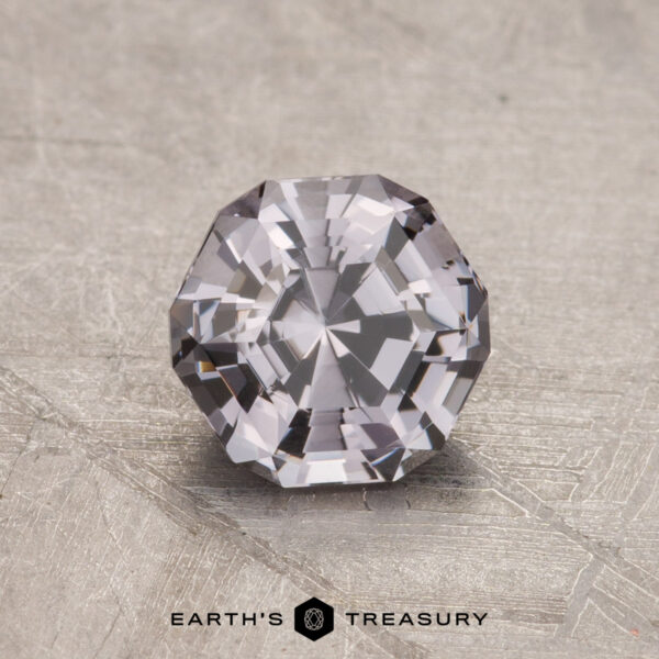 1.11-Carat Gray Spinel A faceted, clear 1.11-carat Spinel with an octagonal shape rests on a textured surface.