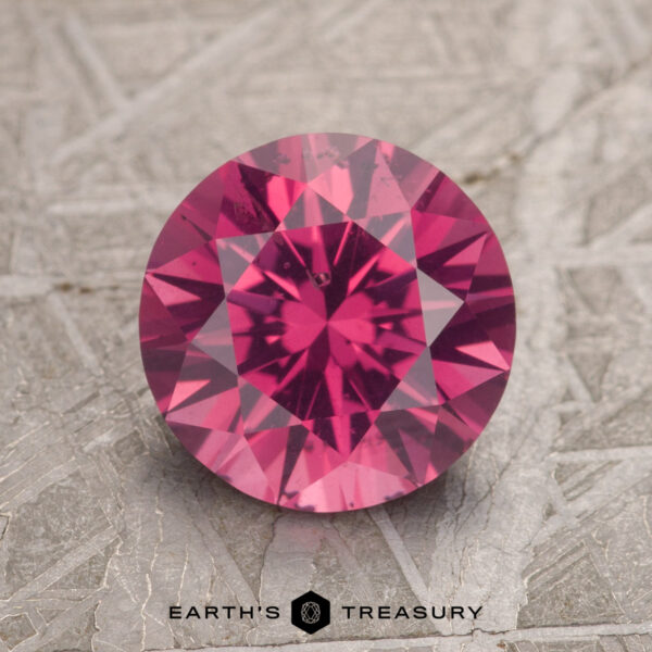 2.26-Carat Magenta Pink Burmese Spinel A 2.26-carat magenta pink Burmese spinel with intricate faceting is displayed on a textured gray surface, featuring the logo "Earth's Treasury" beneath it.
