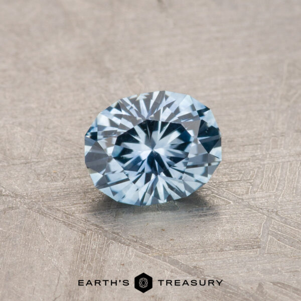 0.80-Carat Montana Sapphire (Heated) A 0.80-carat Montana sapphire with a heated, faceted round cut is displayed on a textured surface.