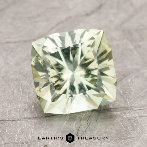 2.43-Carat Light Lime Green California Tourmaline A square-cut green gemstone placed on a textured gray surface, accompanied by the text "EARTH'S TREASURY" underneath. The product is identified as ET1392.
