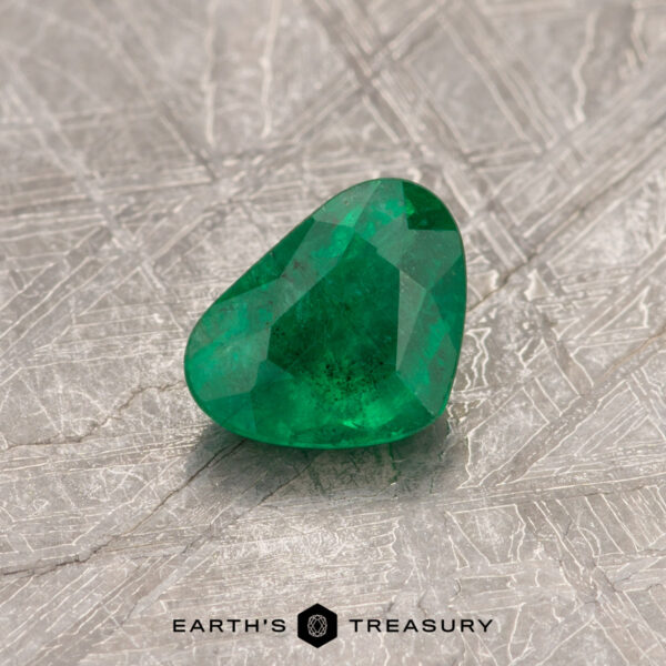0.49-Carat Deep Green Colombian Emerald (Oiled) A 0.49-carat Colombian emerald gemstone resting on a textured surface with the text "Earth's Treasury" below it.