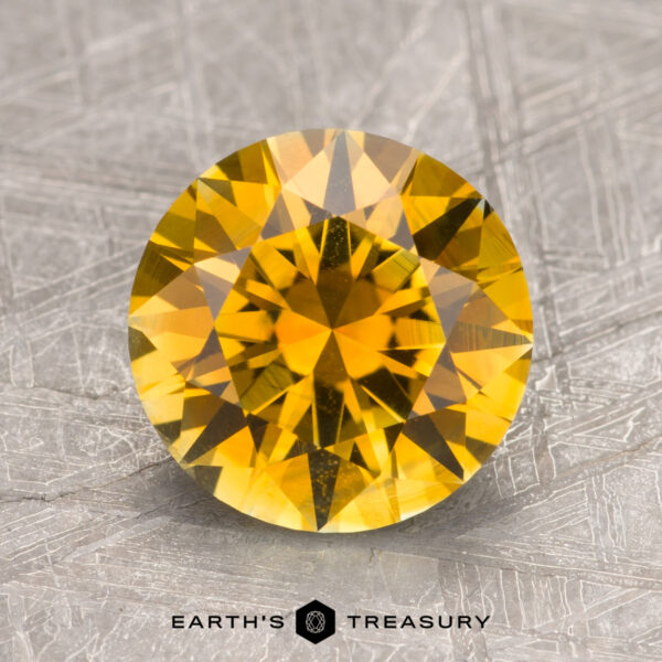 2.75-Carat Golden Yellow Montana Sapphire (Heated) A 2.75-carat golden yellow Montana sapphire with a faceted surface set against a textured silver background, labeled "Earth's Treasury.