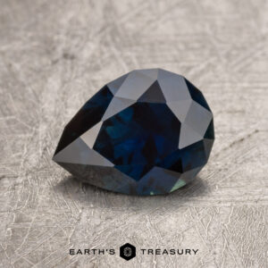 1.71-carat teardrop-shaped Midnight Blue Australian Sapphire on a textured gray surface.
