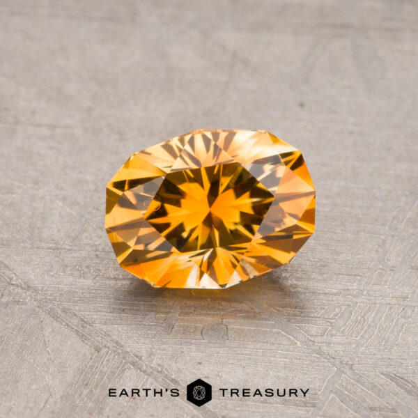 1.09-Carat Montana Sapphire (Heated) A faceted, oval-cut golden yellow 1.09-carat Montana sapphire (heated) displayed on a textured surface. Logo reads "Earth's Treasury.