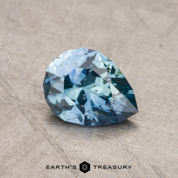 1.03-Carat Montana Sapphire (Heated) A 1.03-carat Montana sapphire, heated and pear-shaped, rests on a textured surface.