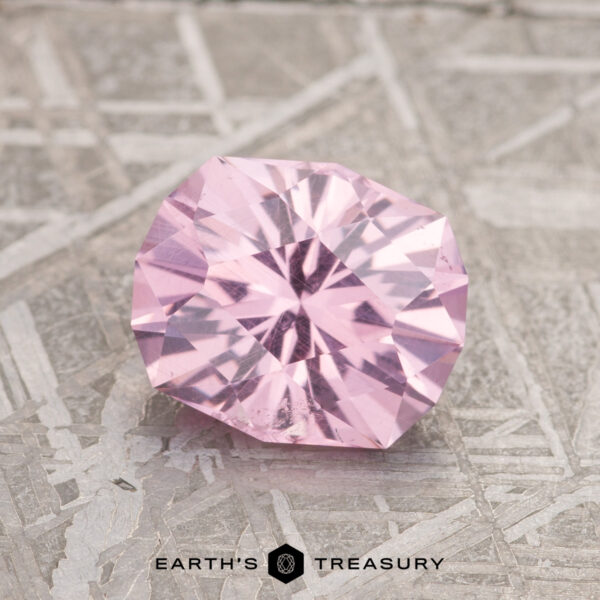 1.87-Carat Lilac Pink Mahenge Garnet A 1.87-carat Lilac Pink Mahenge Garnet is elegantly showcased on a textured gray surface, with the text "Earth's Treasury" appearing at the bottom.