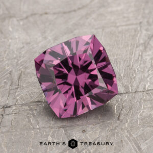 The ET1993, a square-cut purple gemstone with intricate facets, is elegantly displayed on a textured gray surface.