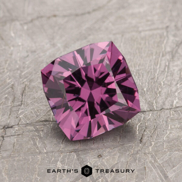 1.53-Carat Magenta Purple to Intense Pink Color Change Garnet The ET1993, a square-cut purple gemstone with intricate facets, is elegantly displayed on a textured gray surface.