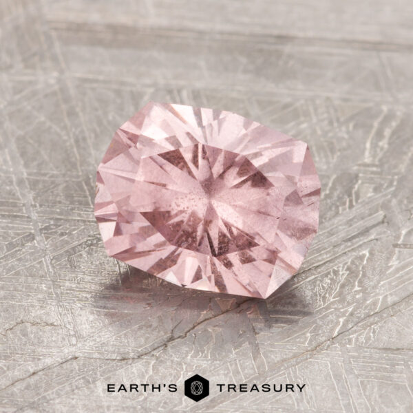 1.79-Carat Pastel Pyrope Garnet 1.79-Carat Pastel Pyrope Garnet gemstone set on a textured gray surface, featuring the logo "Earth's Treasury" at the bottom.