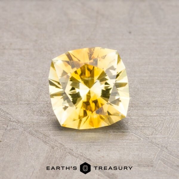 1.06-Carat Montana Sapphire (Heated) A 1.06-carat heated Montana sapphire with a faceted yellow hue rests on a textured surface.