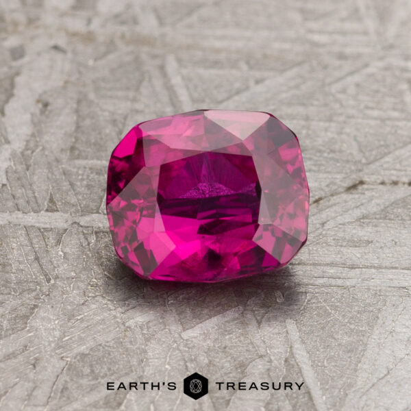 1.32-Carat Ruby (Heated) Close-up of a 1.32-carat faceted, rectangular ruby on a textured gray surface.