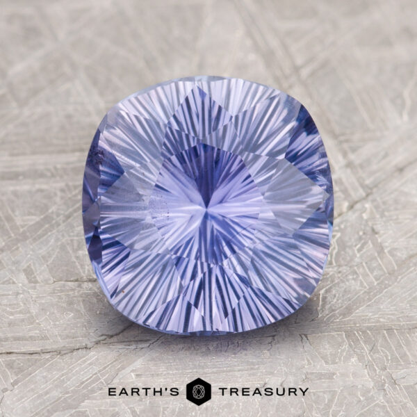 2.60-Carat Ceylon Sapphire A cushion-cut, radiant blue-purple gemstone displayed on a textured surface, labeled as "2.60-Carat Ceylon Sapphire" by Earth's Treasury below it.