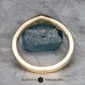 The "Zinnia" band in 14k yellow gold stands upright, framing an orange sapphire on a textured gray surface. The “Earth’s Treasury” logo appears at the bottom.
