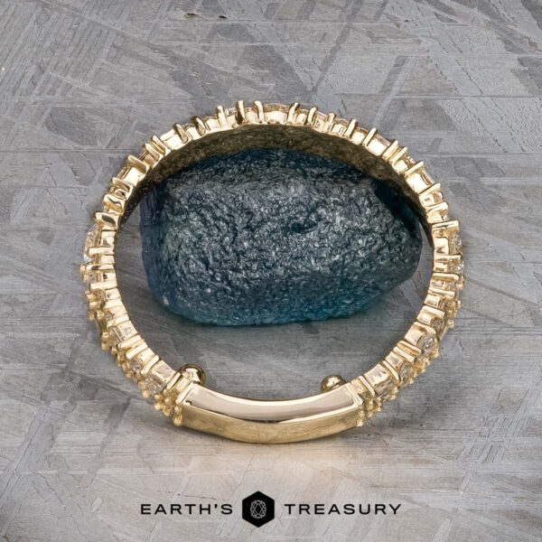 The "Mosaic" band in 14k yellow gold The "Mosaic" band in 14k yellow gold encircles a rough, dark green stone, displayed on a gray patterned surface with "Earth's Treasury" branding below.