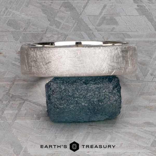 The "Madeira" ring in platinum The "Madeira" ring in platinum rests on a rough blue stone, set against a textured gray background with the text "EARTH'S TREASURY" below.