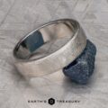 The "Madeira" ring in platinum rests on a rough, dark stone atop a textured metallic surface, with "EARTH'S TREASURY" displayed at the bottom.