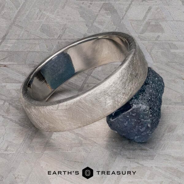 The "Madeira" ring in platinum The "Madeira" ring in platinum rests on a rough, dark stone atop a textured metallic surface, with "EARTH'S TREASURY" displayed at the bottom.
