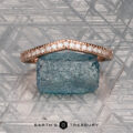 The "Ramona" band in 14K rose gold rests on a rough blue stone atop a geometric silver background, with the “Earth's Treasury” logo displayed below.