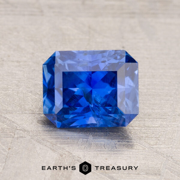 1.65-Carat Ceylon Sapphire A vivid 1.65-carat rectangular, faceted Ceylon Sapphire sparkles brilliantly on a textured surface, its depth enhanced through expert heating.