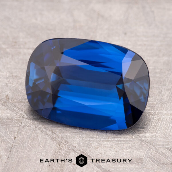 3.29-Carat Ceylon Sapphire (Heated) A rectangular sky blue 3.29-carat Ceylon sapphire, enhanced through heating, with faceted cuts is placed on a textured surface.