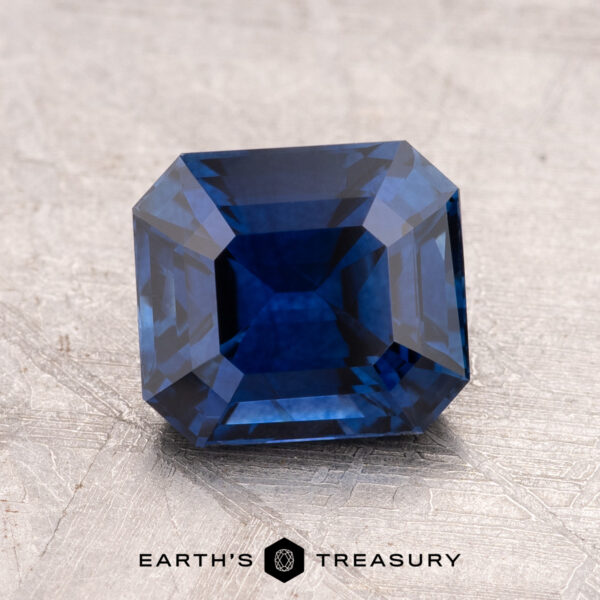 2.24-Carat Ceylon Sapphire (Heated) A faceted 2.24-carat Ceylon Sapphire, possessing a striking light violet-blue hue and rectangular shape, is elegantly placed on a textured surface. The words "Earth's Treasury" are gracefully displayed beneath it.