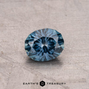 A 0.78-carat Montana sapphire, heated to perfection, is elegantly showcased on a textured surface, captioned "Earth's Treasury.